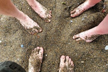 Sandy feet of three beach walkers